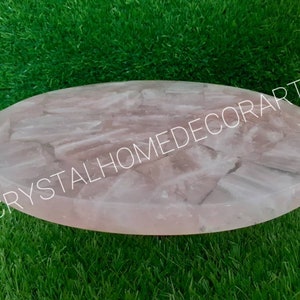 May include: A round, pink, rose quartz serving tray with a polished, smooth surface. The tray is made of natural stone and has a unique, organic pattern.