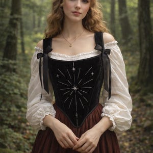 May include: A black velvet corset with a starburst design, paired with a white off-the-shoulder blouse and a burgundy skirt. The corset has a square neckline and is adorned with white stitching. Black ribbons accent the shoulders.