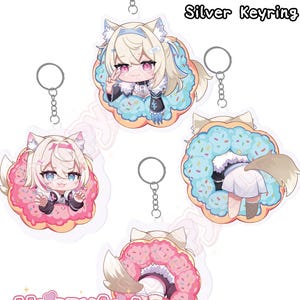 Op de afbeelding: Acryl sleutelhangers met anime-stijl karakters in donut-ontwerpen. Elke sleutelhanger is 7,6 cm hoog en heeft een zilveren sleutelring. De sleutelhangers hebben een cartoonachtige esthetiek met pastelkleuren en de tekst "HappyAmi".