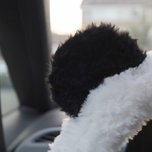 May include: Black and white fuzzy steering wheel cover with a panda bear design.