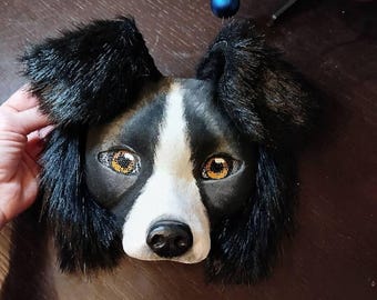 May include: A black and white dog mask with black fur around the ears and a white nose. The mask has realistic details, including brown eyes with gold accents.