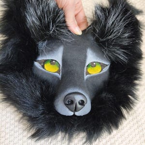 Peut inclure: Un masque de loup noir avec de la fausse fourrure longue et sombre, des oreilles pointues aux pointes argent&eacute;es et des yeux en maille jaune vif. Le museau est sculpt&eacute; avec une finition noire mate lisse et des nuances grises autour des yeux.