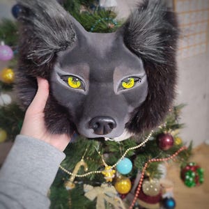Peut inclure: Un masque de loup noir dot&eacute; d'oreilles pointues avec de longs poils sombres, un visage mat lisse et des yeux jaune vif avec des pupilles noires. Le masque pr&eacute;sente un nez noir r&eacute;aliste et des ombres d&eacute;taill&eacute;es autour des yeux.