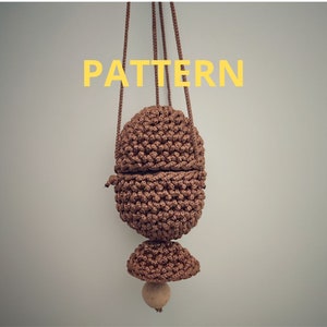 May include: A brown crocheted bag with a wooden bead at the bottom. The bag is hanging from two cords and has a pattern of small stitches.