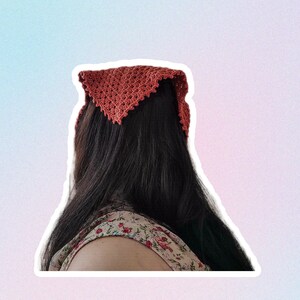 Op de afbeelding: Een vrouw met lang donker haar die een terracotta geh&auml;kelde bandana om haar hoofd draagt.