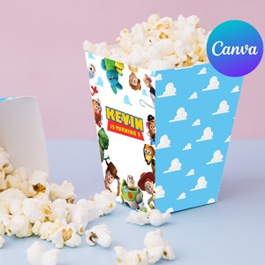 Op de afbeelding: Twee popcornbakjes, &eacute;&eacute;n rechtop en &eacute;&eacute;n omgekiept, gevuld met popcorn. De bakjes zijn lichtblauw met witte wolken en karakterillustraties. De tekst "KEVIN IS TURNING 3" staat op de voorkant.