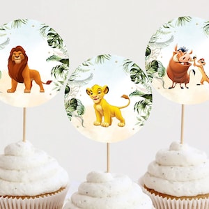 May include: Three cupcakes topped with round toppers featuring characters from The Lion King. The toppers have a watercolor background with green leaves and gold accents. The characters include Simba, Mufasa, Timon, and Pumbaa.