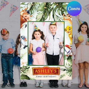 Może przedstawiać: Rekwizyt do fotobudki z zieloną ramą, tropikalnymi liśćmi i postaciami z Króla Lwa. Tekst "ASHLEY'S FIRST BIRTHDAY!" jest wyświetlany na dole. Dzieci pozują z balonami i czapeczkami.