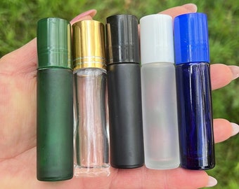 May include: Five glass roller bottles with different colored caps. The bottles are green, clear, black, white, and blue.