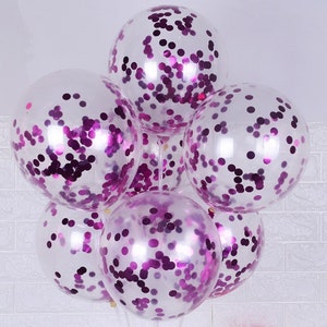 May include: A bunch of clear balloons filled with purple confetti. The balloons are tied together and ready for a party.