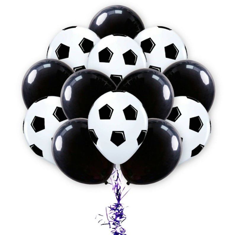 Może przedstawiać: Gromada czarno-białych balon&oacute;w w kształcie piłki nożnej. Balony są związane razem purpurową wstążką.