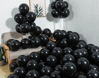 May include: A large group of black balloons, some are tied together in clusters, others are scattered on a couch and floor.