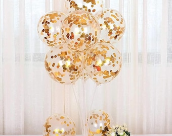 May include: A cluster of clear balloons with gold confetti inside, arranged on a clear stand. The balloons are tied together with clear string.