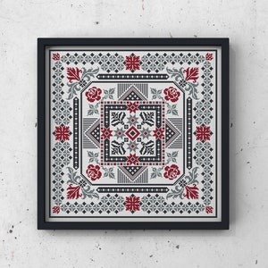 May include: A framed cross-stitch embroidery with a geometric pattern in shades of gray and red. The design features a central square with a starburst pattern and four stylized floral motifs in the corners.
