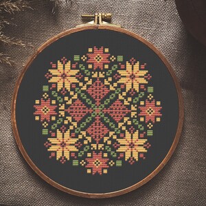 May include: A circular embroidery hoop with a black fabric background and a colorful floral design stitched in red, yellow, and green thread.