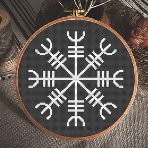 May include: A black and white embroidery hoop with a white Vegvisir symbol on a black background.