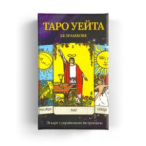 Puede incluir: Una caja de cartas de Tarot con fondo negro y diseño de cielo estrellado. La caja presenta el texto "Таро Уейта" en letras doradas, seguido de "Безрамкове" en letras doradas más pequeñas. La caja muestra tres cartas: "Місaль", "Маг" y "Сонце". La caja también incluye el texto "78 карт з українською інструкцією".