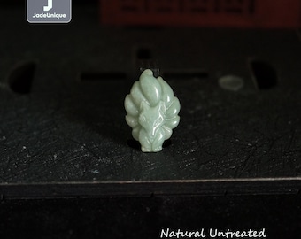 Op de afbeelding: Een lichtgroene Burmese jadeiet vossen hanger. De vos heeft negen staarten en is gedetailleerd gesneden. De tekst in de afbeelding luidt "Natural Untreated Burmese Jadeite Fox". De hanger wordt op een donkere ondergrond getoond.