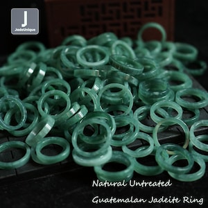 May include: A large pile of natural, untreated jadeite rings in a light green color. The rings are stacked on top of each other, creating a textured and visually appealing display.  Natural Untreated Guatemalan Jadeite Ring.