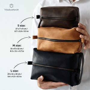 May include: Three rectangular leather toiletry bags in dark brown, tan, and black. The small bag measures 6.7 x 2.8 x 3.5 inches, the medium 8.3 x 3.1 x 4.7 inches, and the large 9.4 x 4.3 x 6.3 inches. Each features a zipper and side handle.