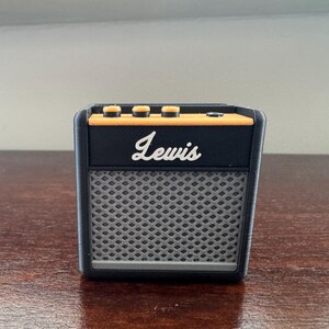 May include: A black and orange electric guitar amplifier with the word "Lewis" printed on the front.