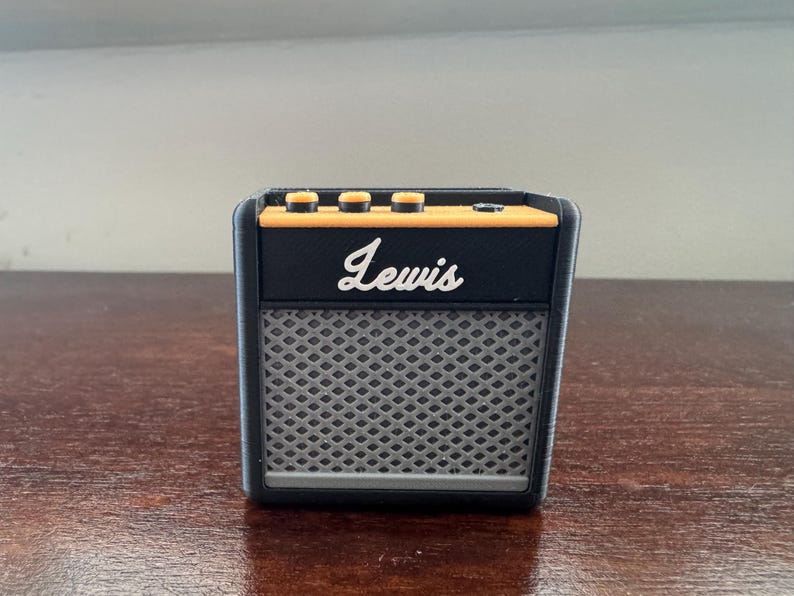 May include: A black and orange electric guitar amplifier with the word "Lewis" printed on the front.