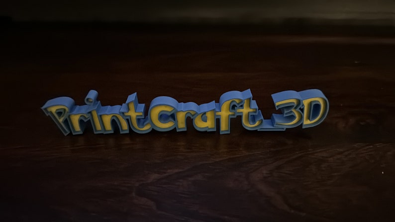 May include: A blue and yellow 3D printed sign that reads "PrintCraft 3D".