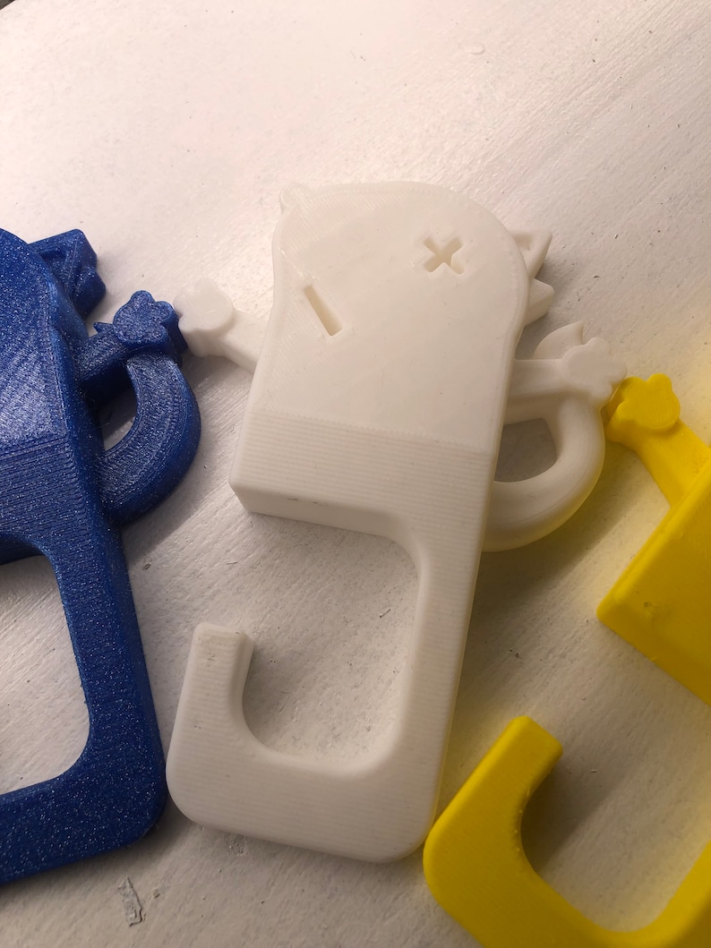 May include: Three 3D printed doorstop hooks in the shape of a cartoon cat. The hooks are blue, white, and yellow.
