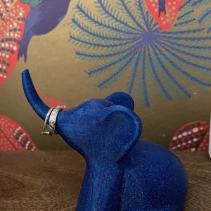 Op de afbeelding: Een blauwe glitter olifant ringhouder. De olifant heeft een opgetrokken slurf en een ring is op de slurf geplaatst.