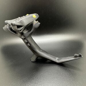 May include: A black 3D printed dragon figurine with yellow eyes. The dragon is posed in a standing position with its head tilted back and its tail curled around its body.