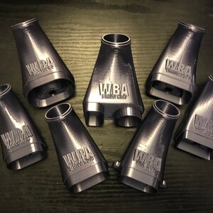 Może przedstawiać: Osiem szarych, plastikowych części wydrukowanych w 3D z tekstem "WBA" i "Blackout" na każdej części.