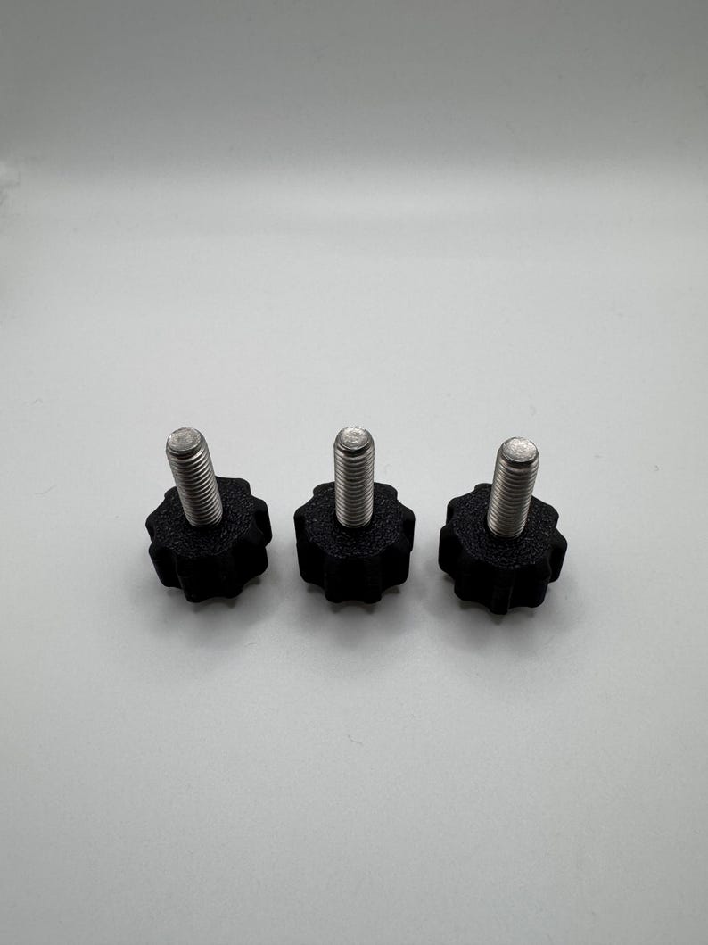May include: Three black star-shaped knobs with silver threaded bolts. The knobs are made of a textured plastic material. The bolts are made of a shiny metal. The knobs are evenly spaced against a white background.