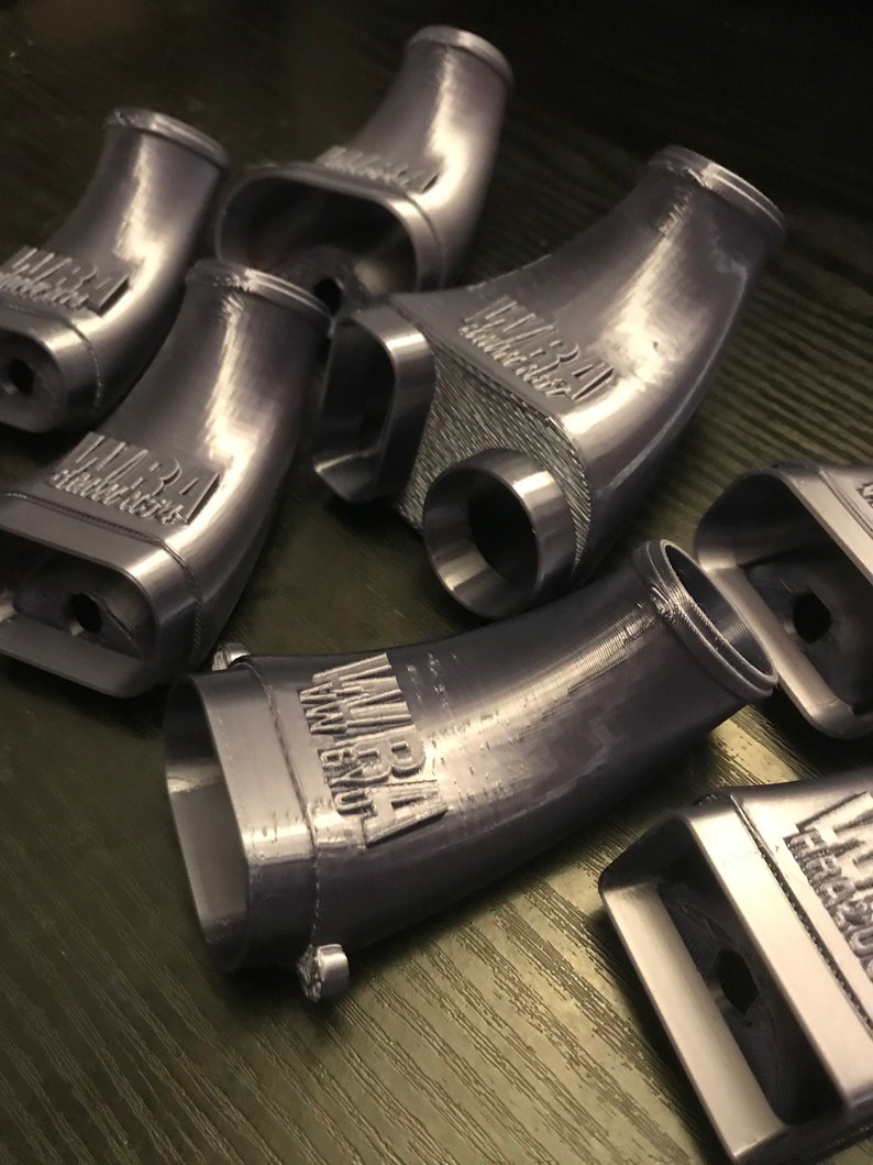 May include: A set of six gray 3D printed plastic parts with the text "MIRA" printed on each part. The parts are shaped like curved tubes.