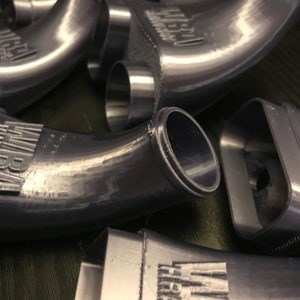 May include: Close-up of several gray plastic intake manifolds with the word "Intake" printed on them.