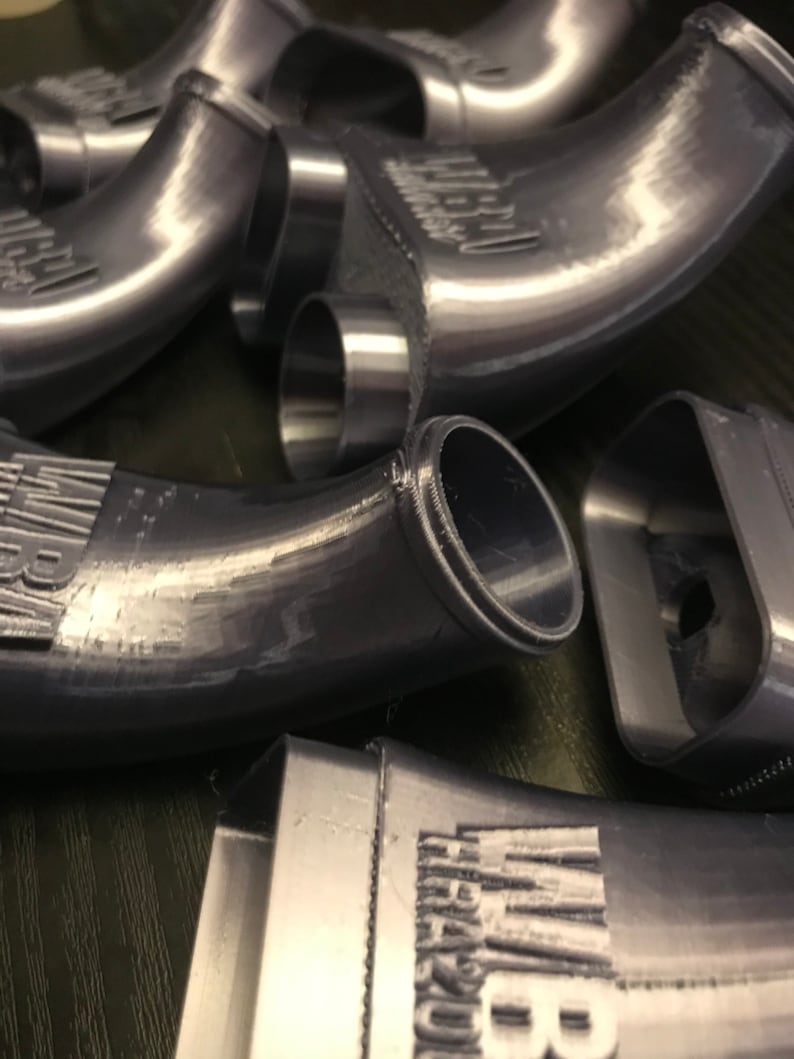 May include: Close-up of several gray plastic intake manifolds with the word "Intake" printed on them.