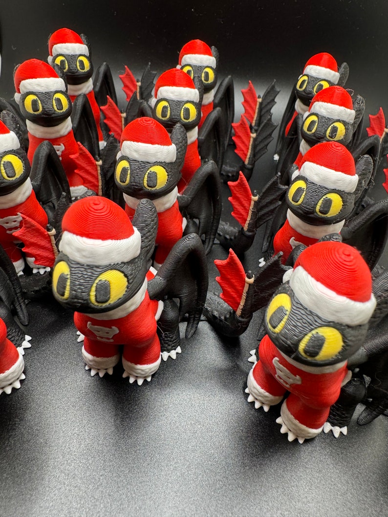 May include: A group of black and red Christmas ornaments shaped like dragons. The ornaments have yellow eyes and white accents.