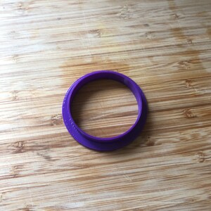 Puede incluir: Cortador de galletas de pl&aacute;stico en forma de anillo de color morado.