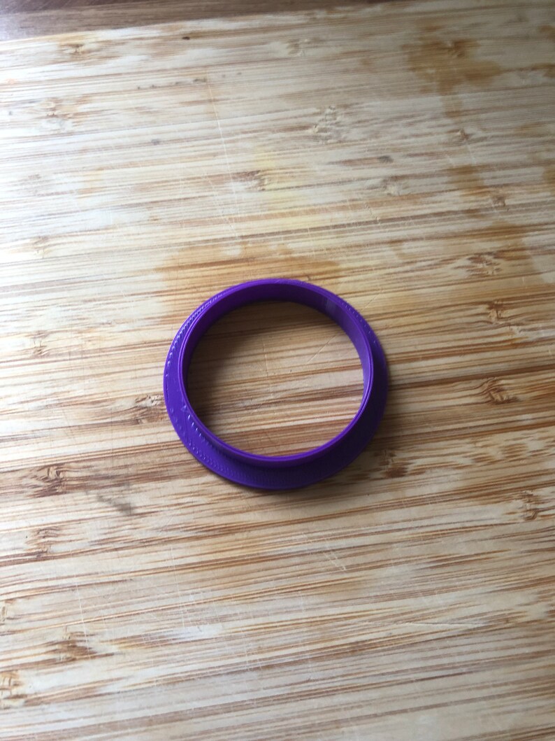 Puede incluir: Cortador de galletas de pl&aacute;stico en forma de anillo de color morado.