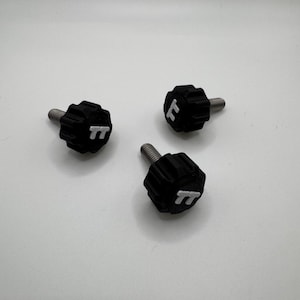 May include: Three black knobs with a silver threaded bolt. Each knob has a white "TT" logo on the top. The knobs are arranged on a white background.