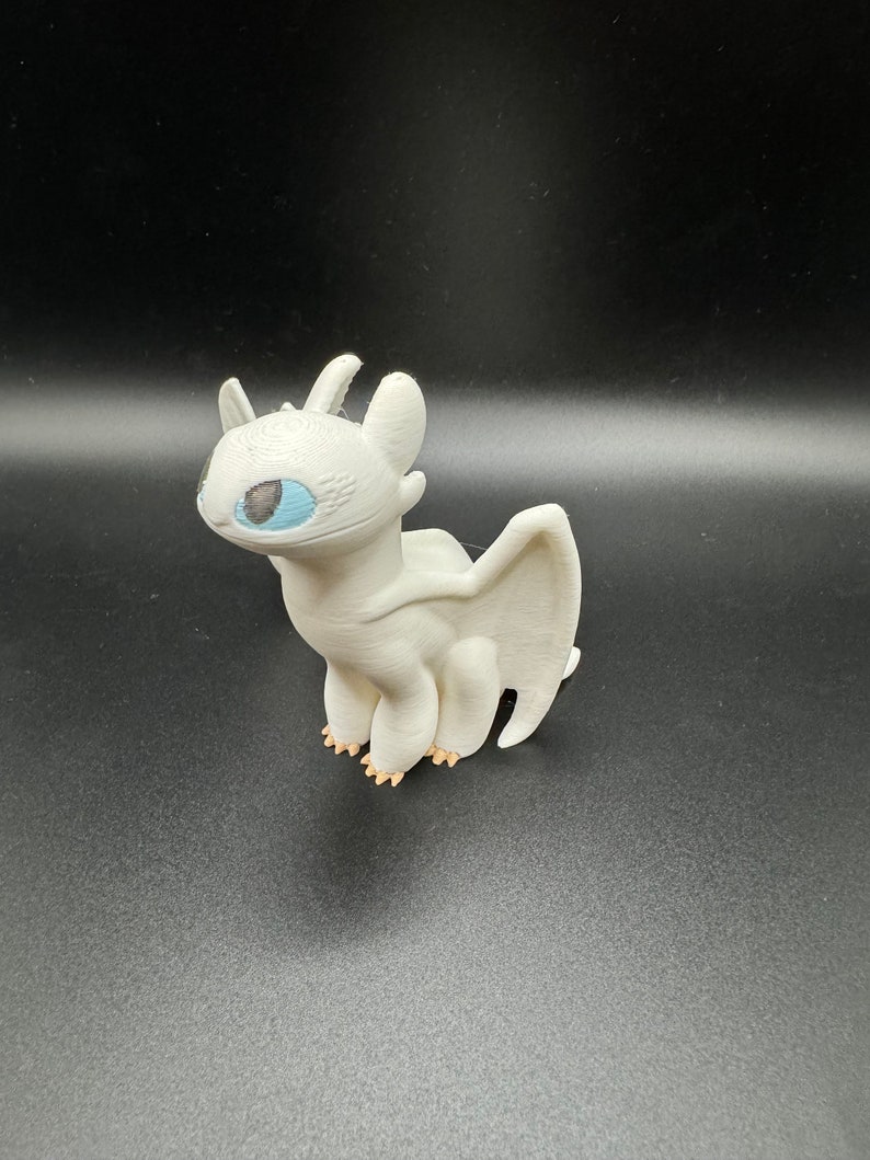 May include: White dragon figurine with blue eyes. The dragon is standing on all fours with its wings spread out behind it.
