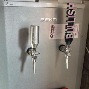 May include: A silver refrigerator with two beer taps, one labelled "Bullish". The refrigerator is labelled "BEKO" and has a digital display on the top left.