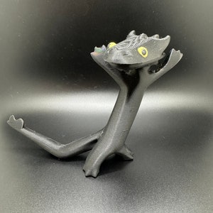 May include: A black 3D printed figurine of a dragon with yellow eyes. The dragon is standing on its hind legs with its front legs raised in the air. The dragon's tail is curled around its body.