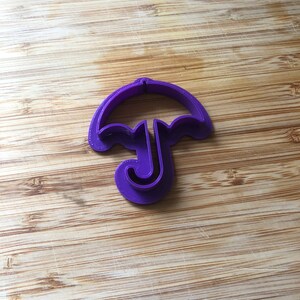 Puede incluir: Cortador de galletas de pl&aacute;stico morado con forma de paraguas.