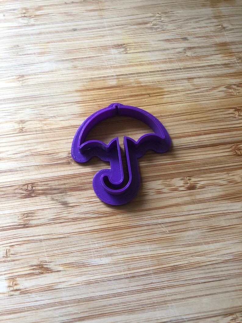 Puede incluir: Cortador de galletas de pl&aacute;stico morado con forma de paraguas.