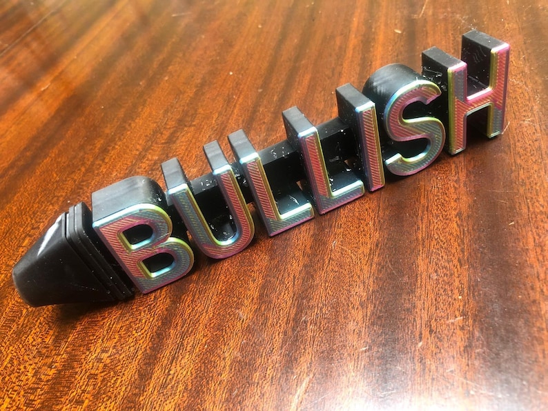 May include: A black plastic sign with the word "BULLISH" in rainbow iridescent letters.
