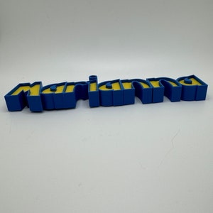 May include: A blue and yellow 3D name sign that reads "mariana".