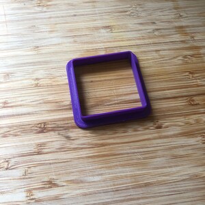 Puede incluir: Un cortador de galletas cuadrado de pl&aacute;stico morado.