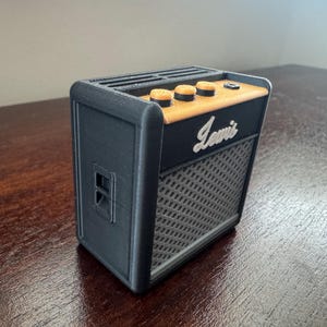 May include: A black and orange electric guitar amplifier with the word "Lewitt" printed on the front.
