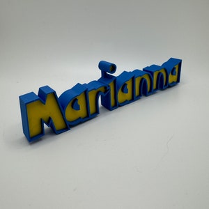 May include: A 3D printed name sign that says "Marianna" in blue letters with yellow fill. The letters are raised and have a rounded, playful font.