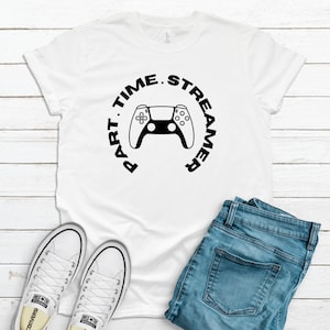 May include: White t-shirt with a black circle graphic featuring a video game controller and the text "Part Time. Streamer."